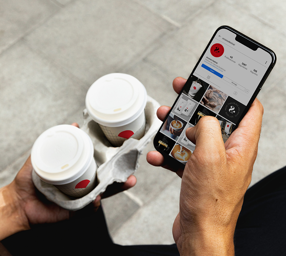 Mann ist im Instagram-Profil der Kaffeerösterei und hält dabei 2 Kaffeebecher